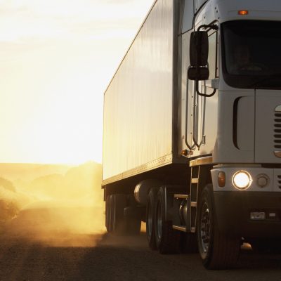Semi-truck driving on dusty dirt road
