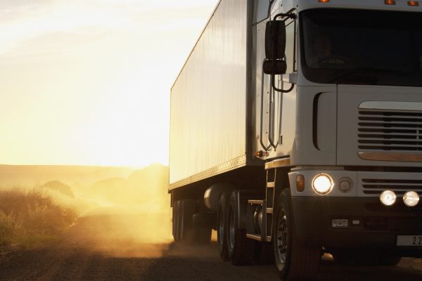 Semi-truck driving on dusty dirt road