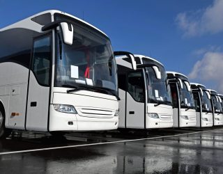 Front right side shot on the white tourist buses in a row on the parking.